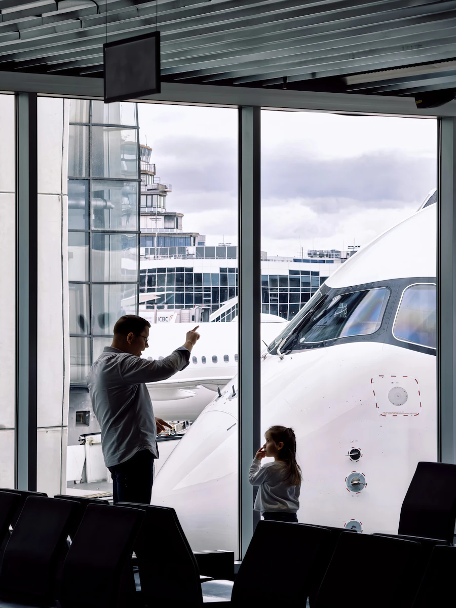 Papá e hija mirando un avión desde la sala de embarque