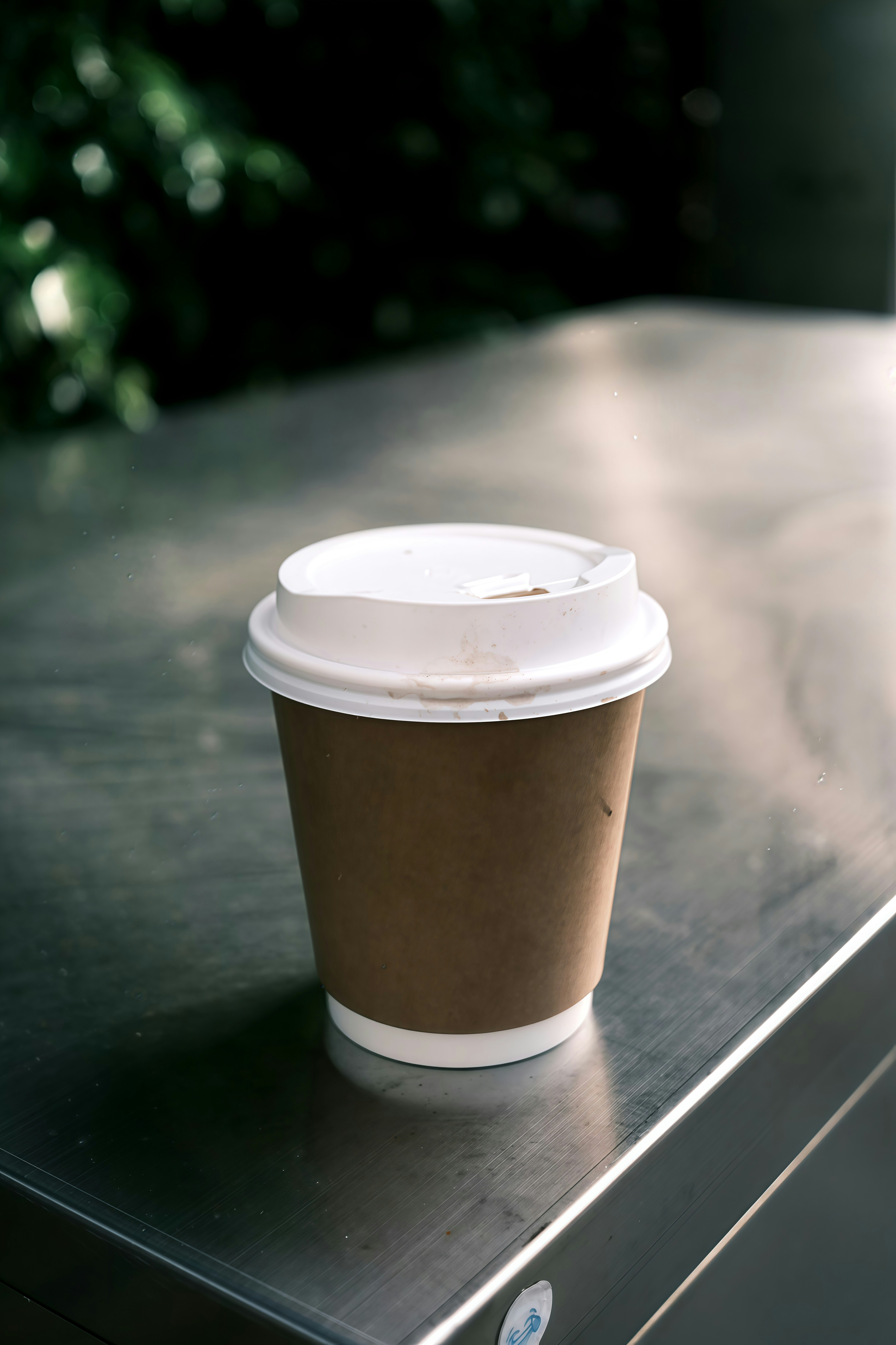 A disposable coffee cup on a metallic surface.