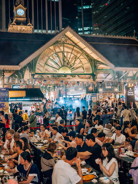 Crowded outdoor market with people eating at tables.