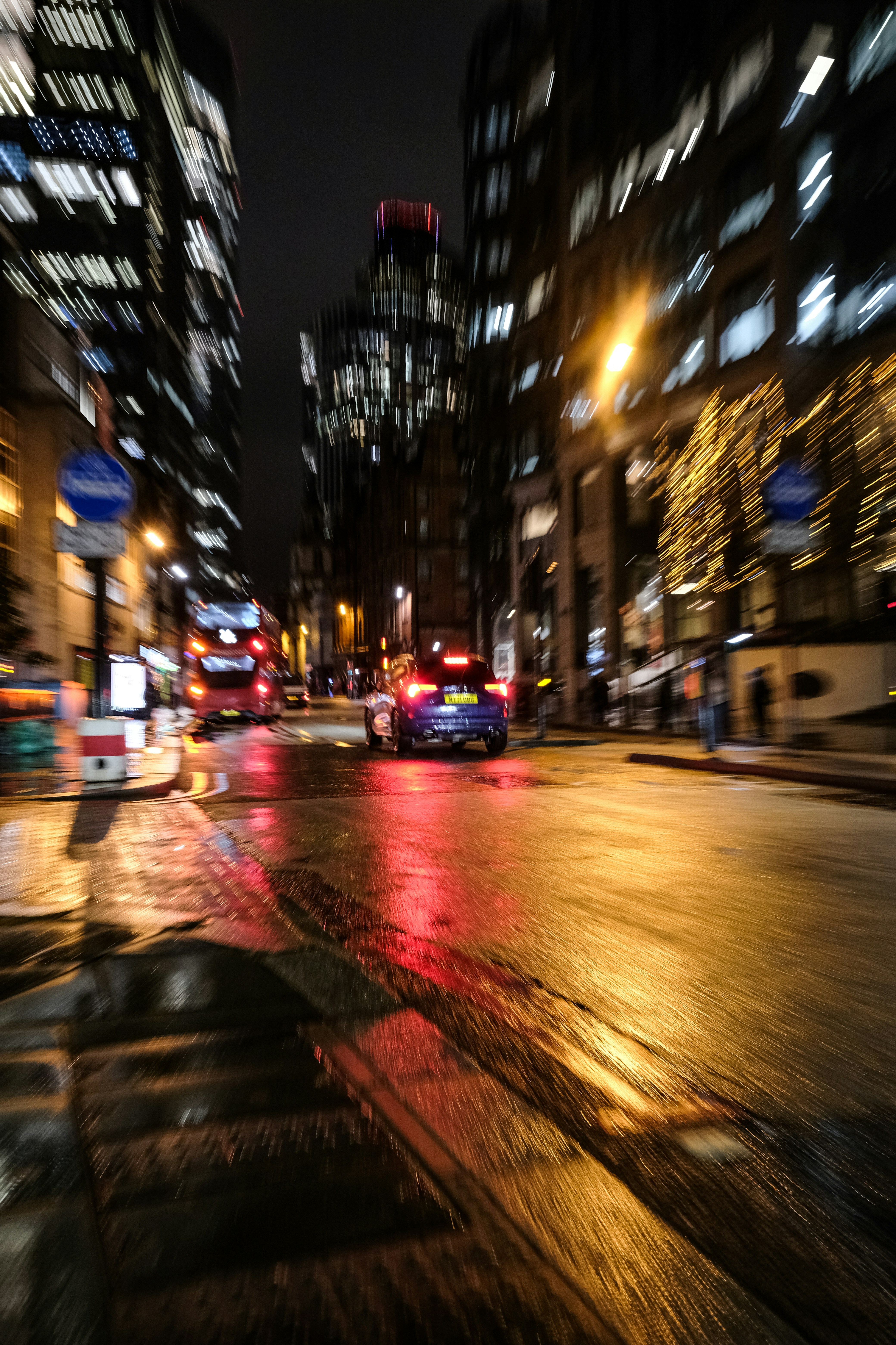 Blurry city street at night with wet reflections.