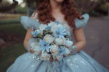 Woman in blue dress holding white and blue flowers