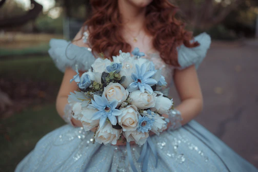 Woman in blue dress holding white and blue flowers