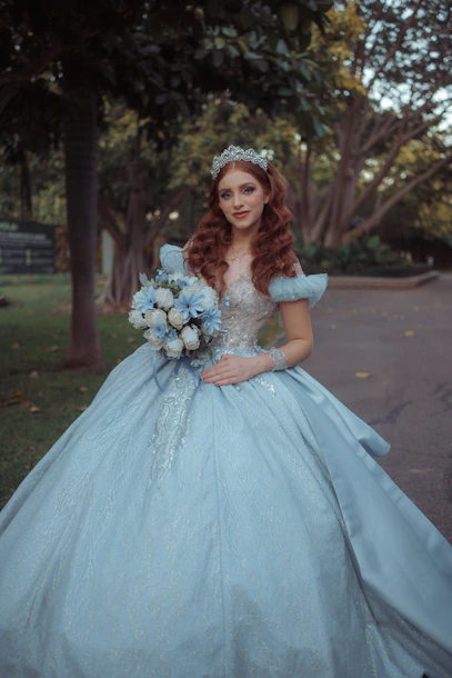 Young woman in a blue ball gown holding a bouquet.