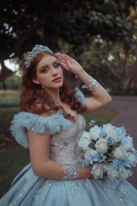 Woman in a tiara and blue dress holding flowers