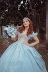 A woman in a blue ball gown holding a bouquet.