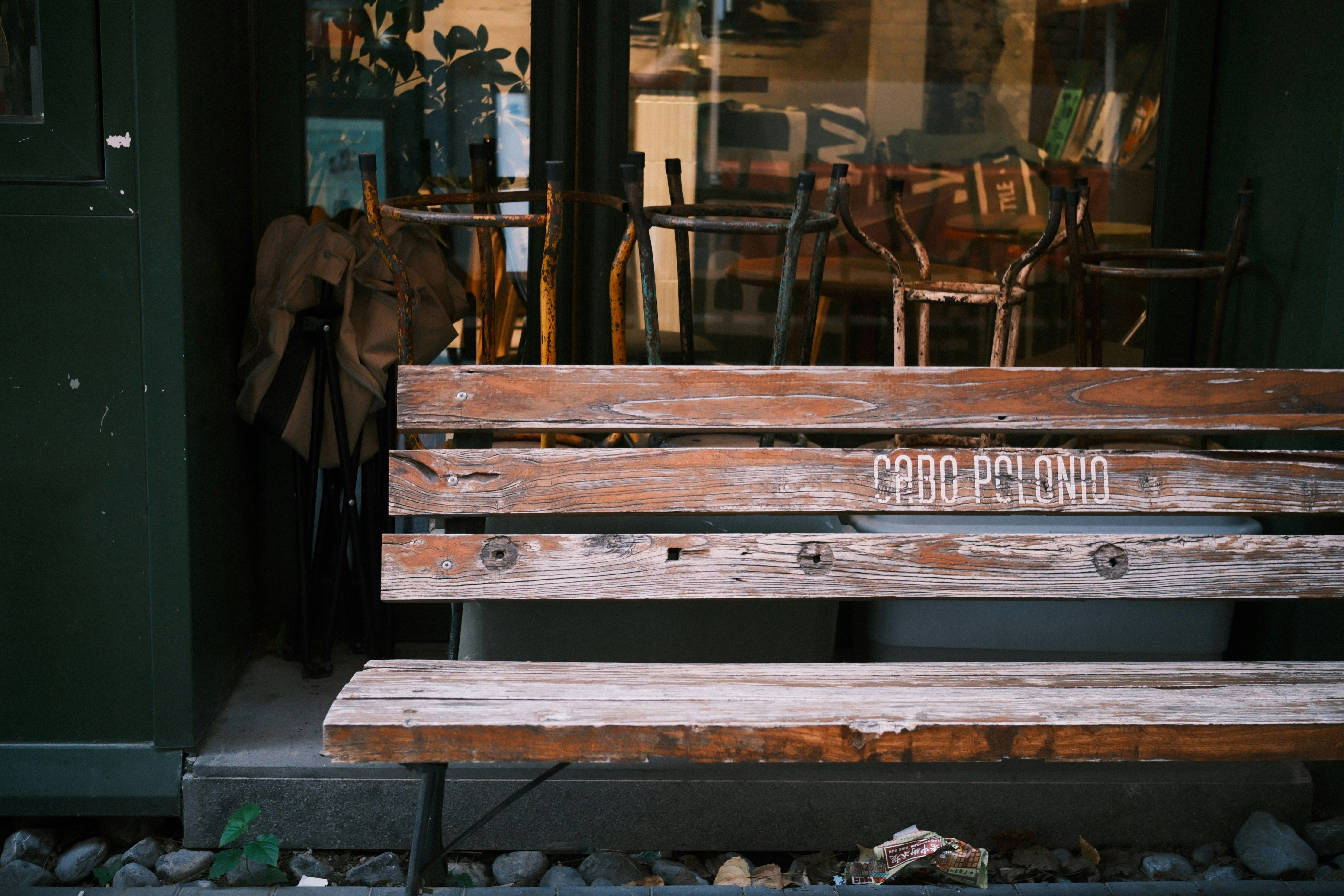 A weathered wooden bench with text on its backrest.