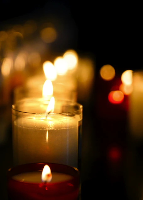 Several lit candles glowing in the dark.