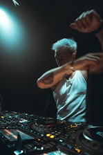 Dj performing with arms raised at a console
