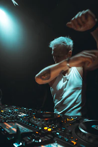 Dj performing with arms raised at a console