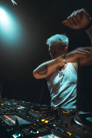 Dj performing with arms raised at a console