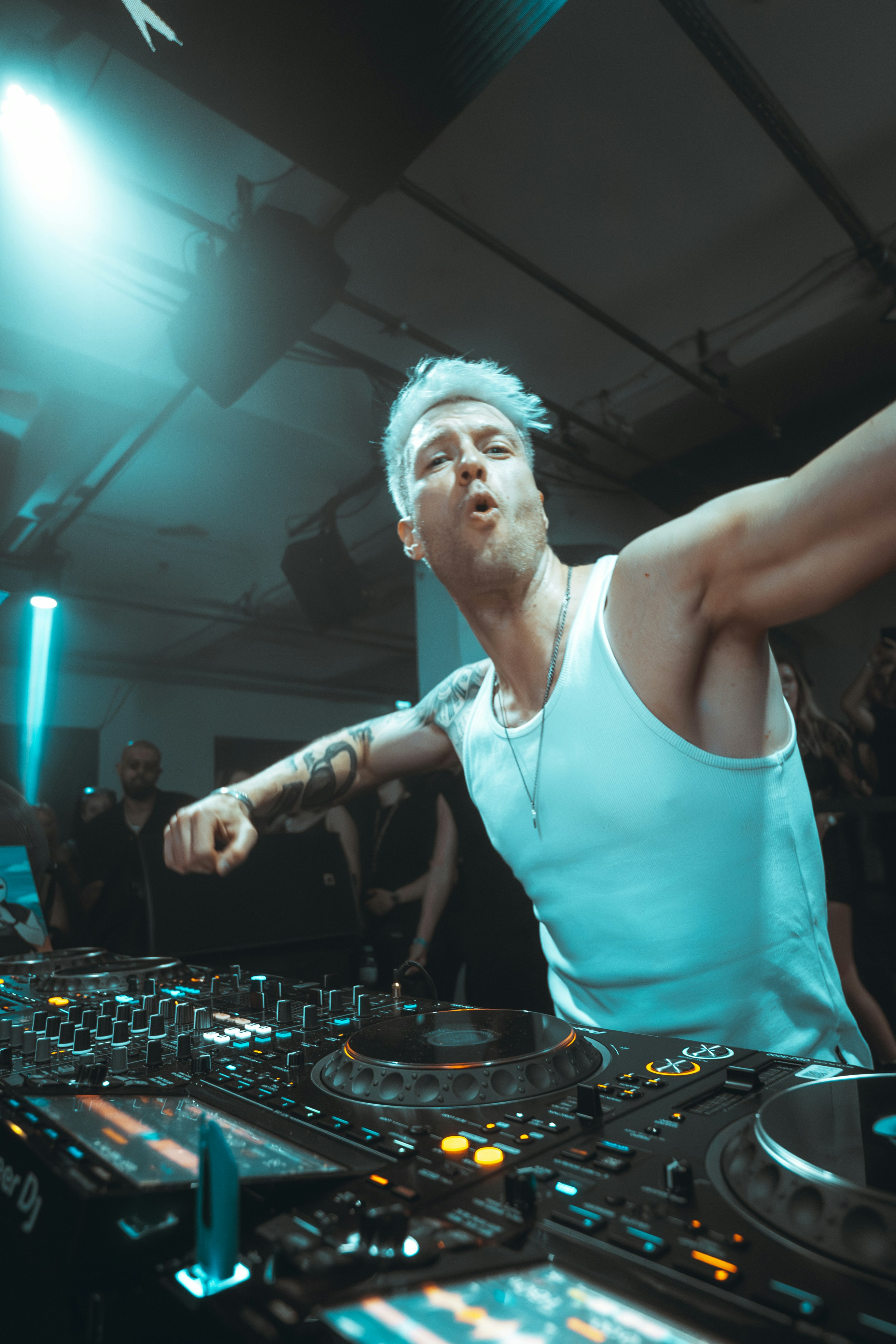Dj performing with arms outstretched at nightclub