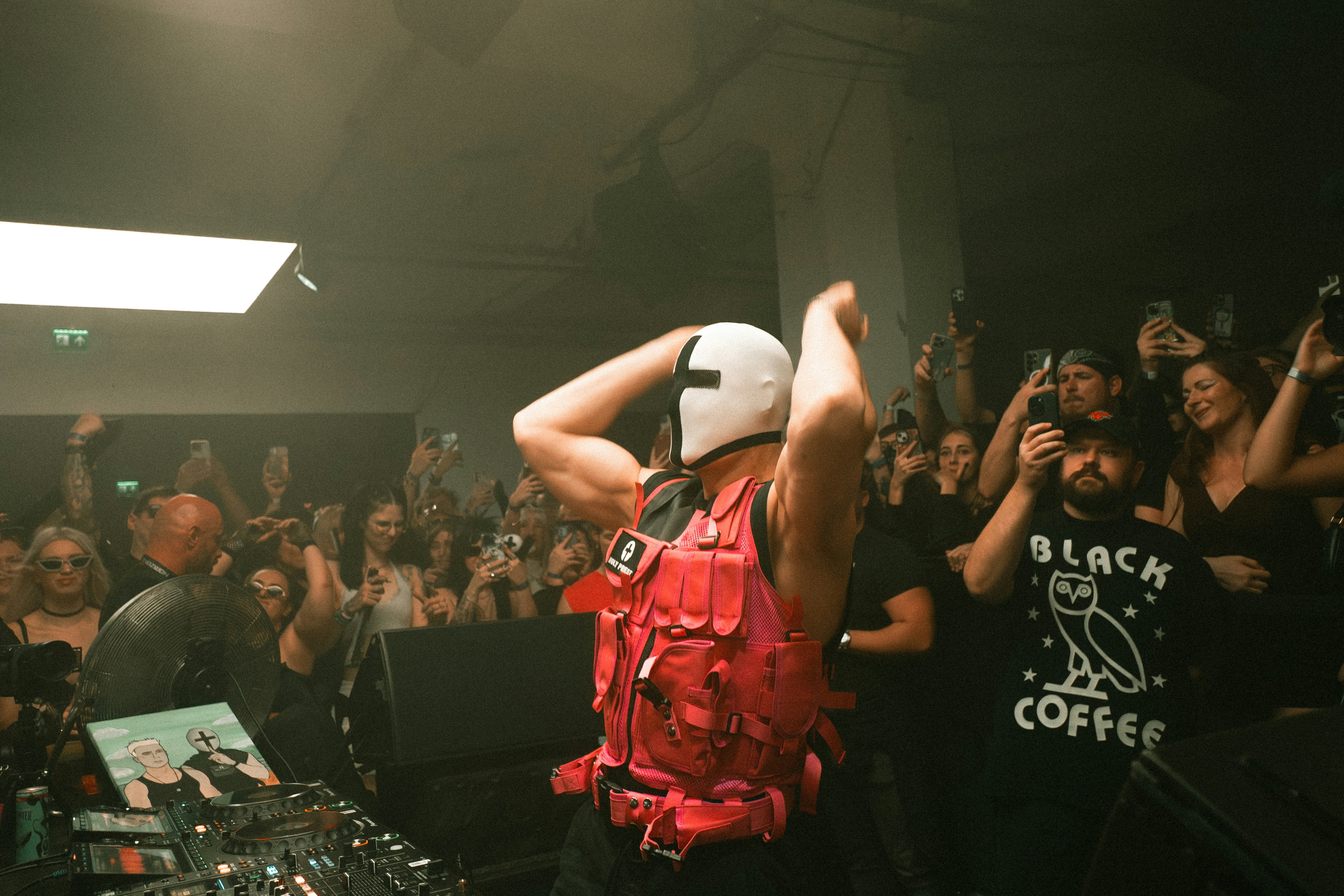 Dj in mask and red vest performs for crowd
