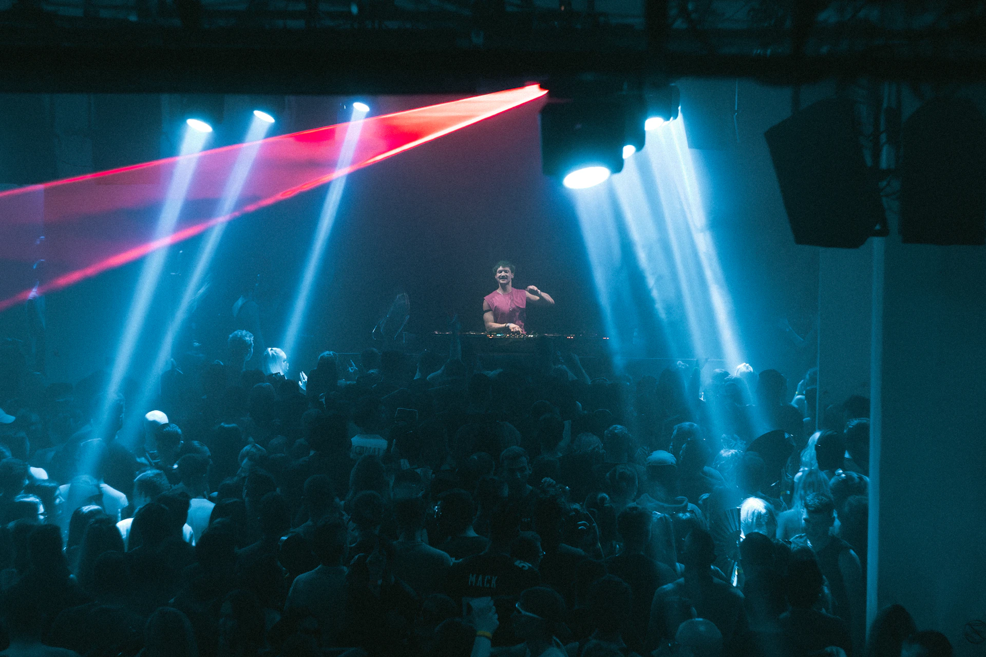 Dj performing for a crowd under blue and red lights