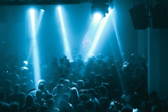Crowd dancing under blue spotlights at a concert.