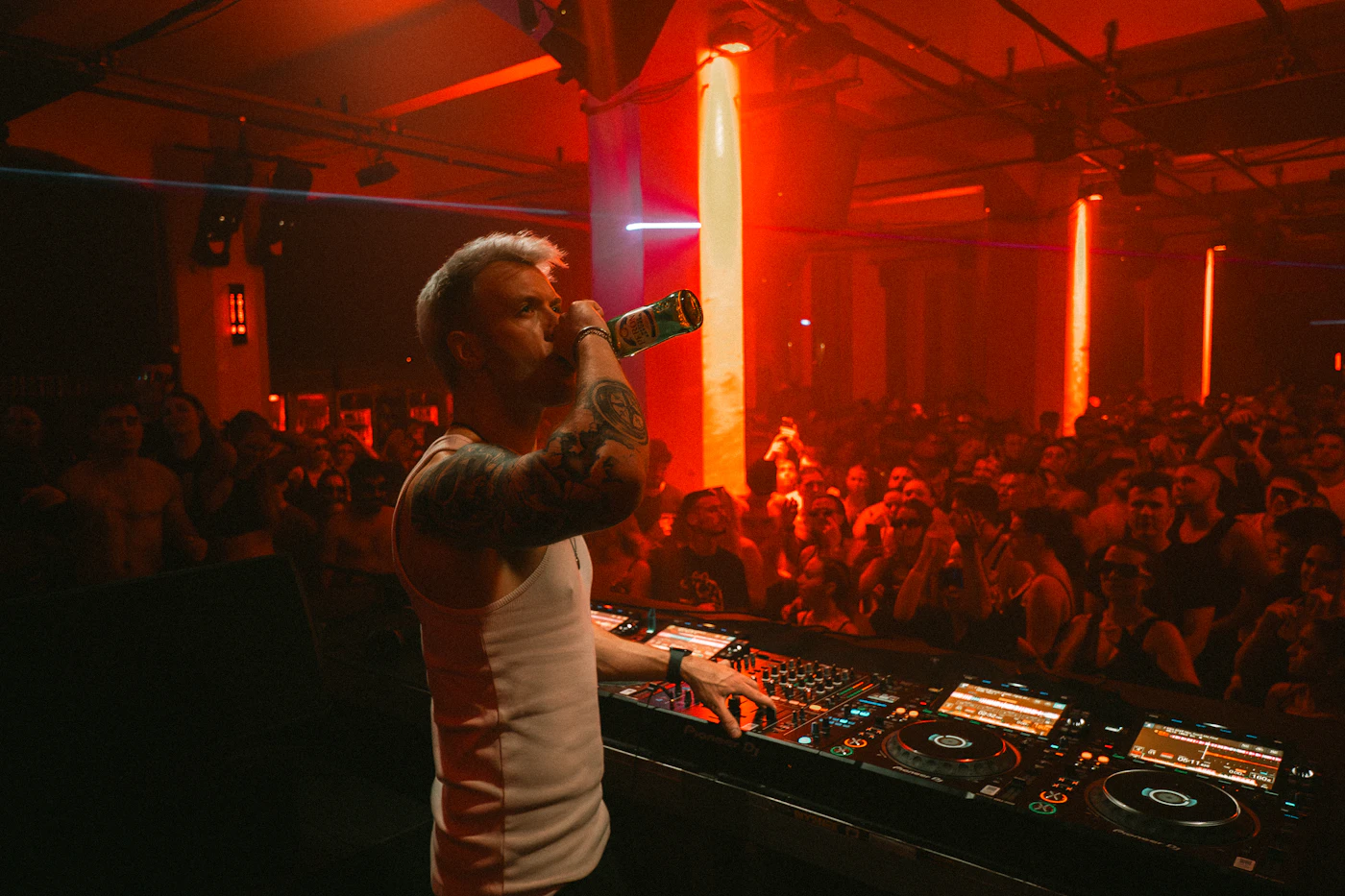 Fiesta con DJ y público bajo iluminación roja de escenario