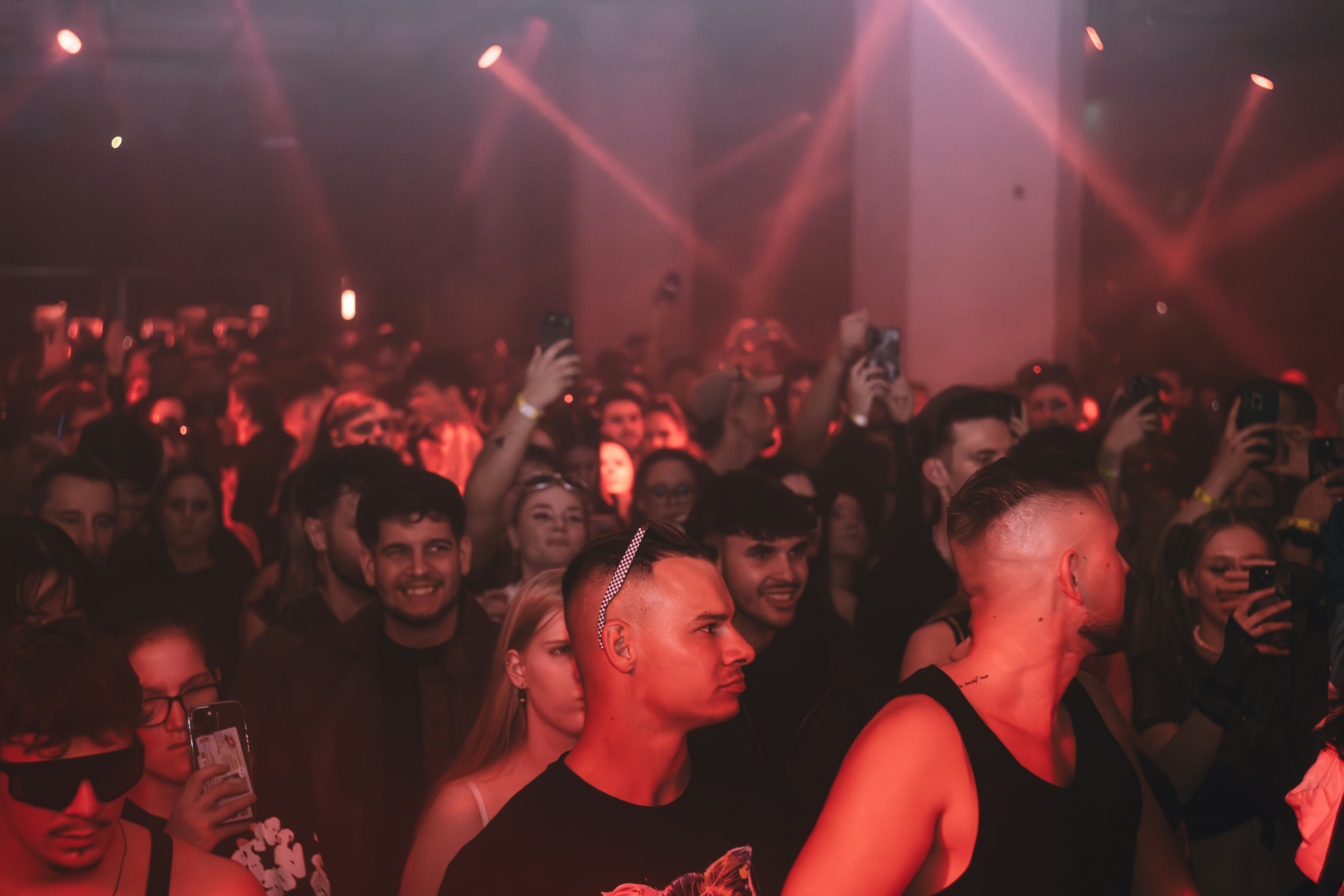 Crowd enjoying a concert with red stage lights.