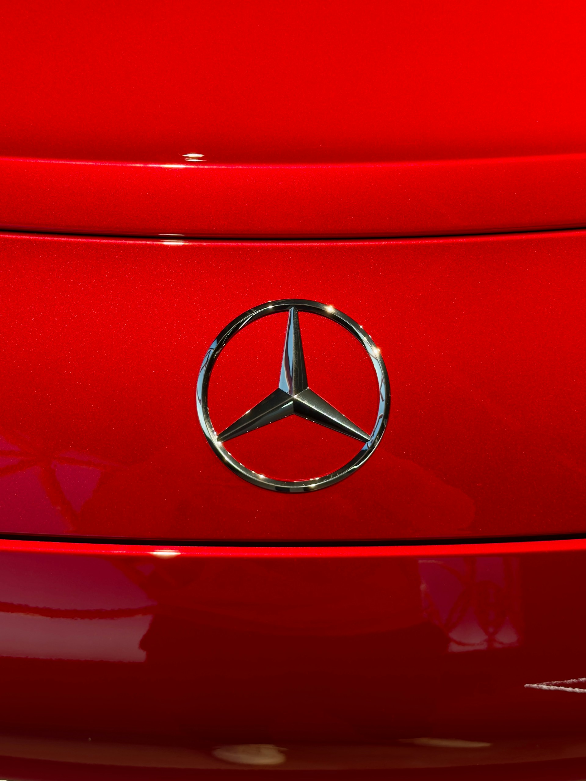 Close up of a red mercedes-benz car emblem.
