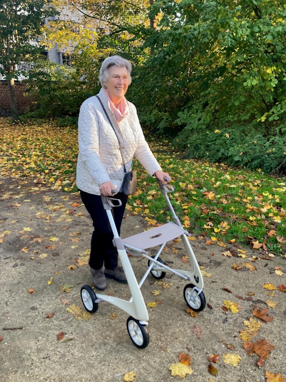 Elderly woman walking with a walker in autumn park.