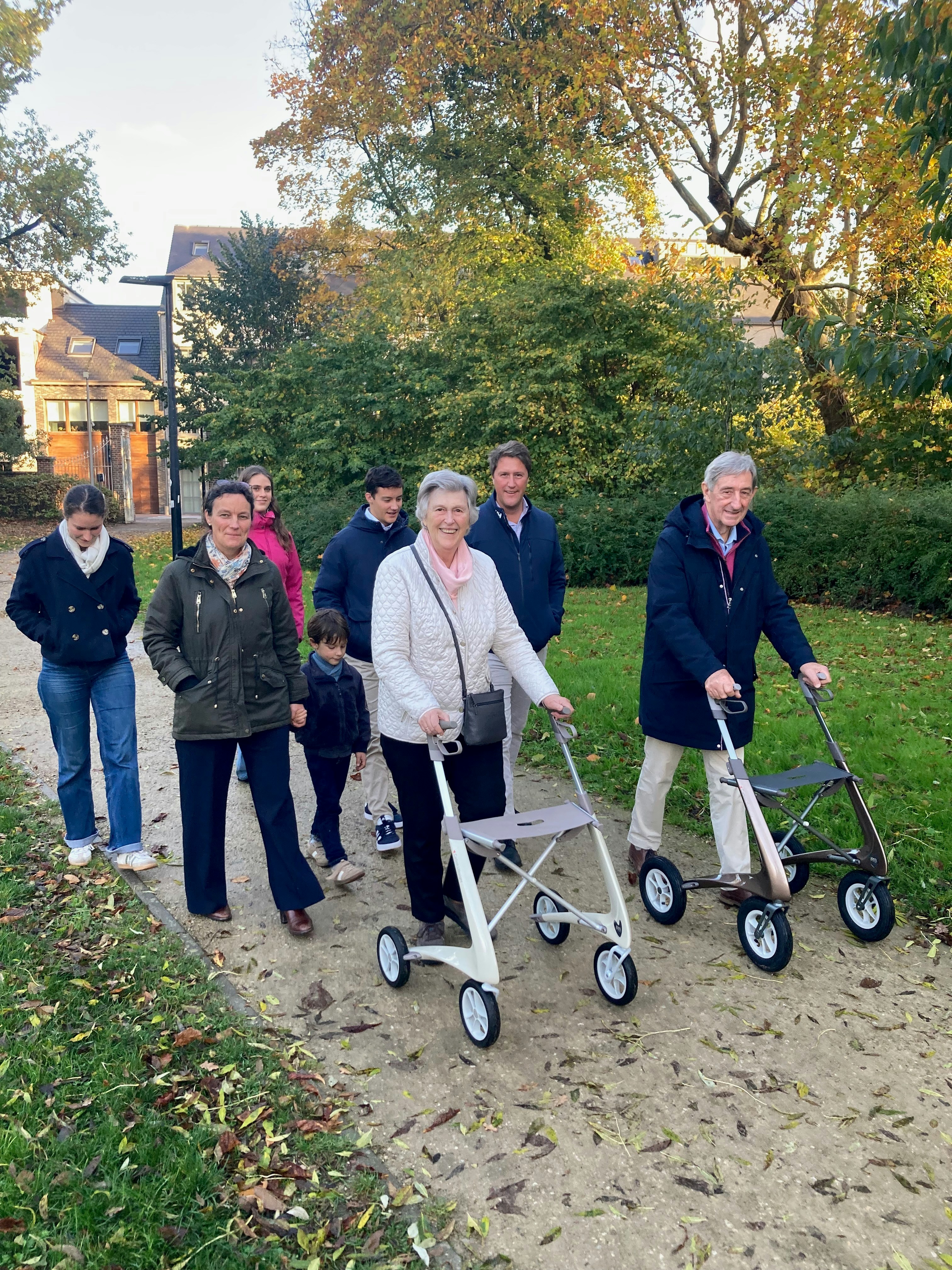 A group of people walking in a park with walkers.