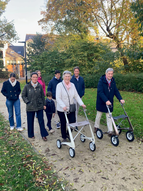 A large family walking in a park with the seniors using walkers.