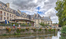River flows past buildings with a bridge in background.