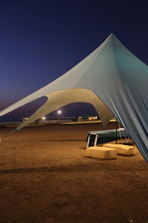 A large tent structure on a beach at dusk.