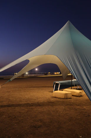 A large tent structure on a beach at dusk.