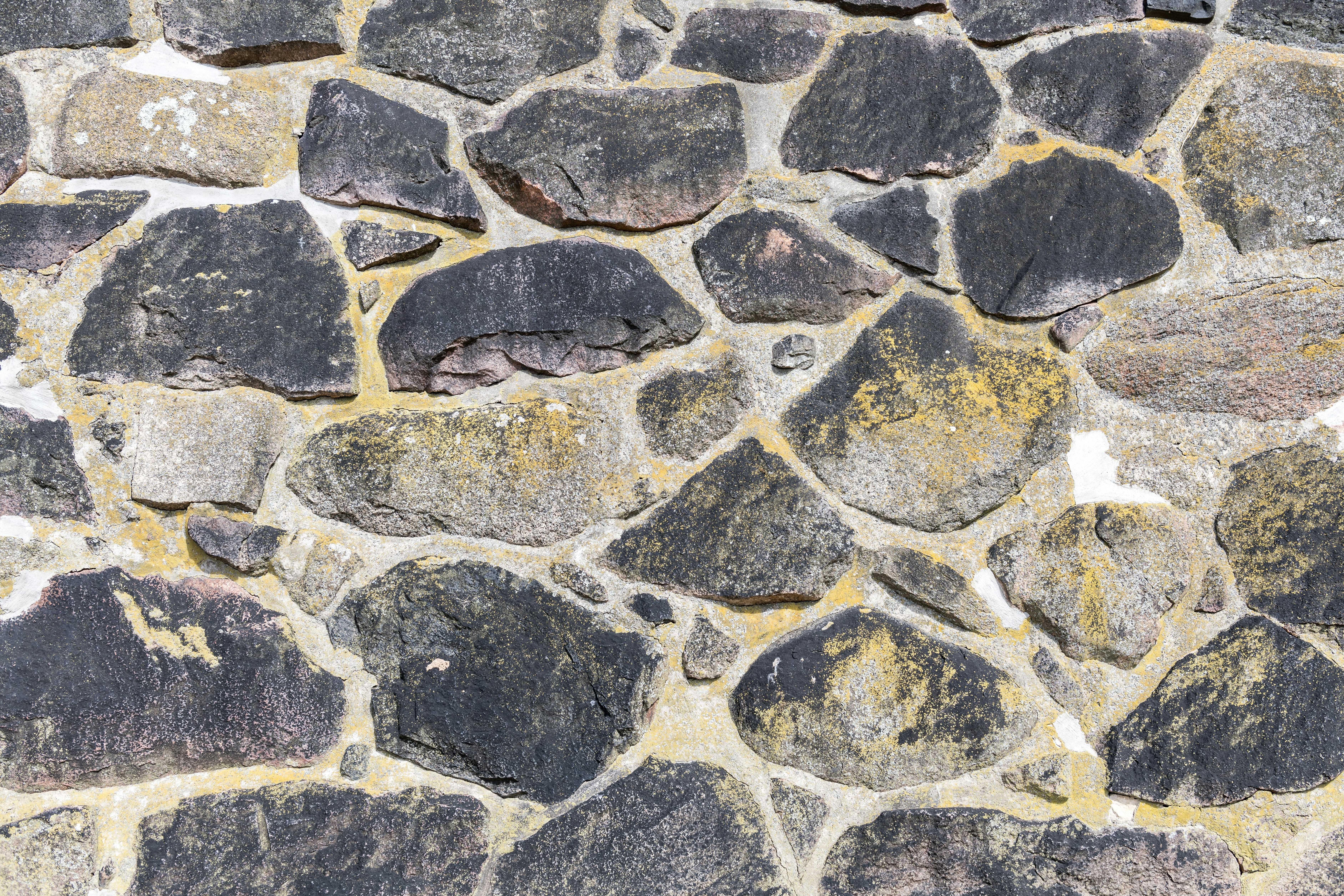 A rough stone wall with varied grey and tan rocks.