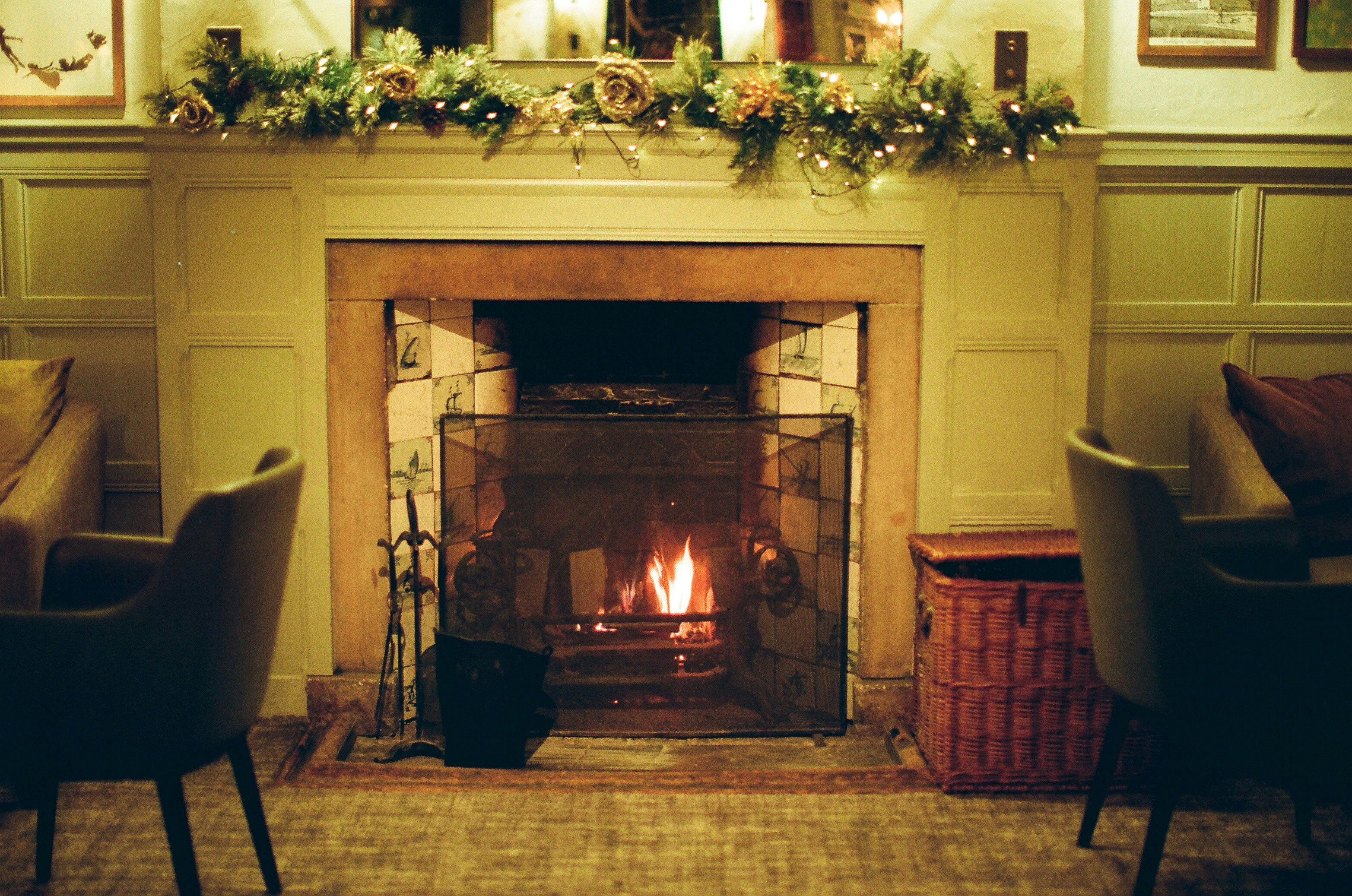 A cozy fireplace with chairs and decorations.