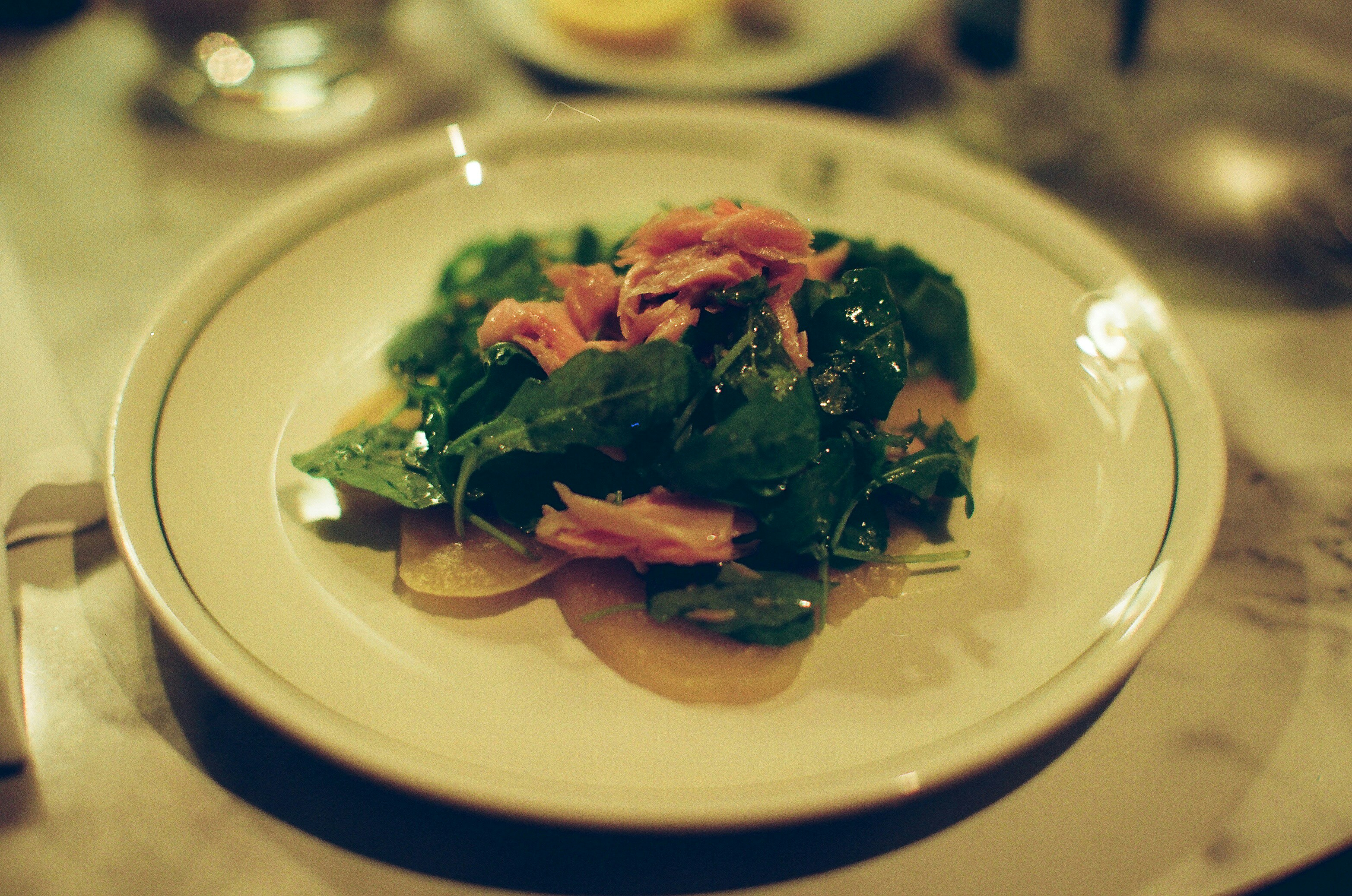 Spinach salad with salmon on a white plate