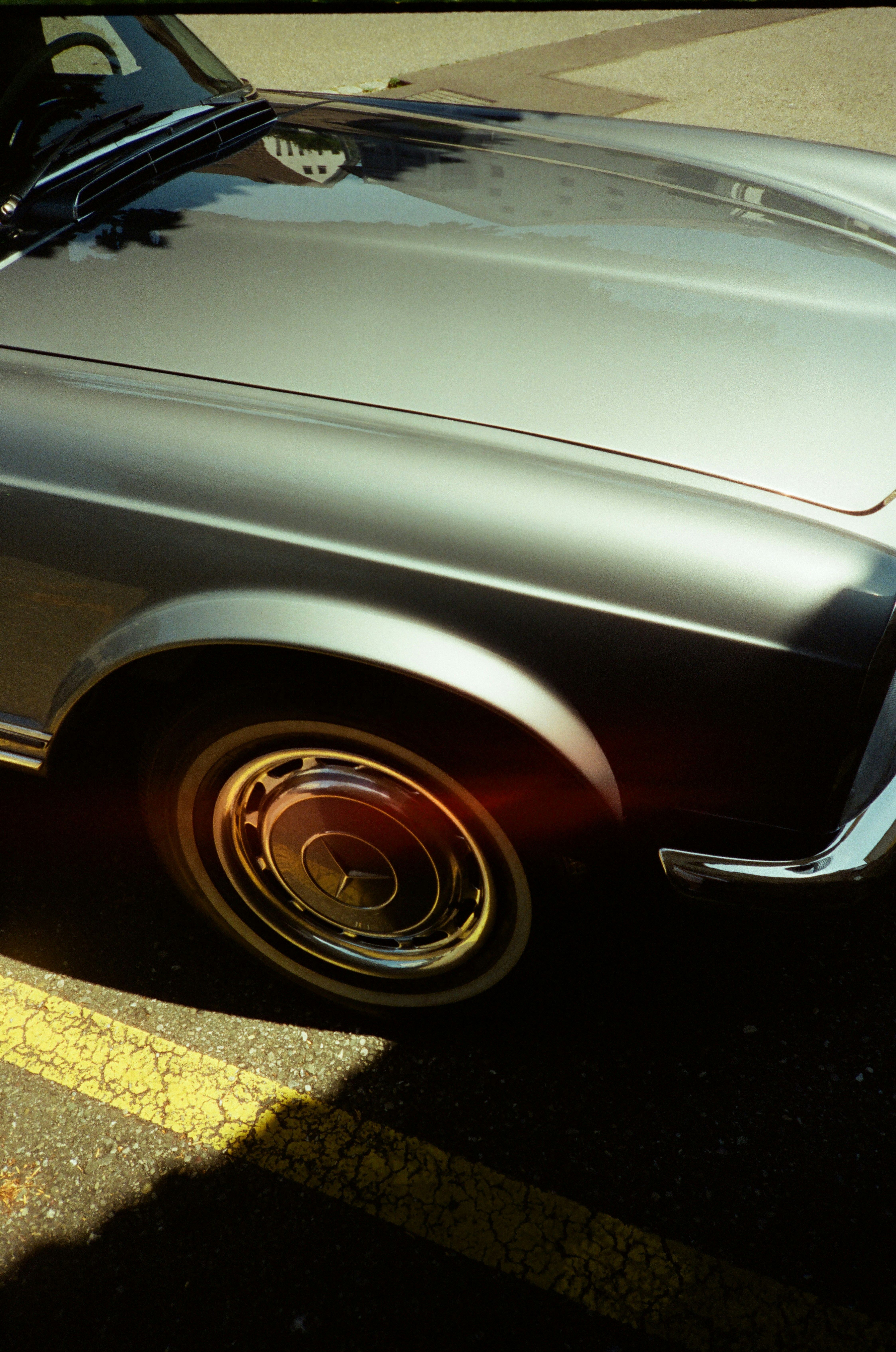 Close-up of a vintage silver car wheel and fender.