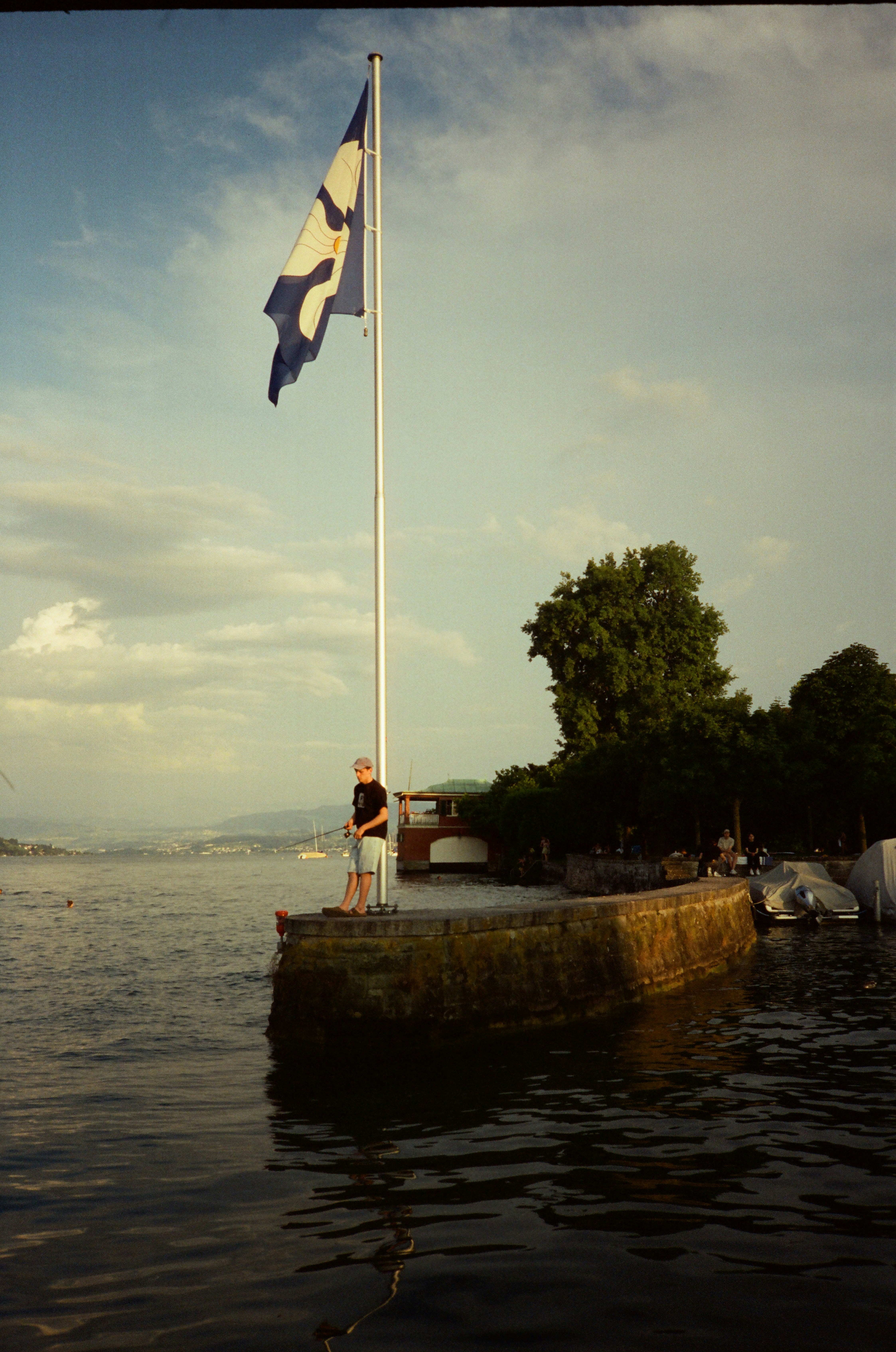 Man stands by flag on a pier overlooking water