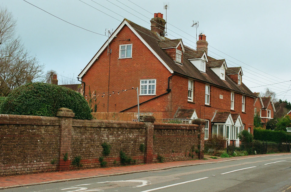 Charming red brick house with three chimneys and lush greenery on a street corner