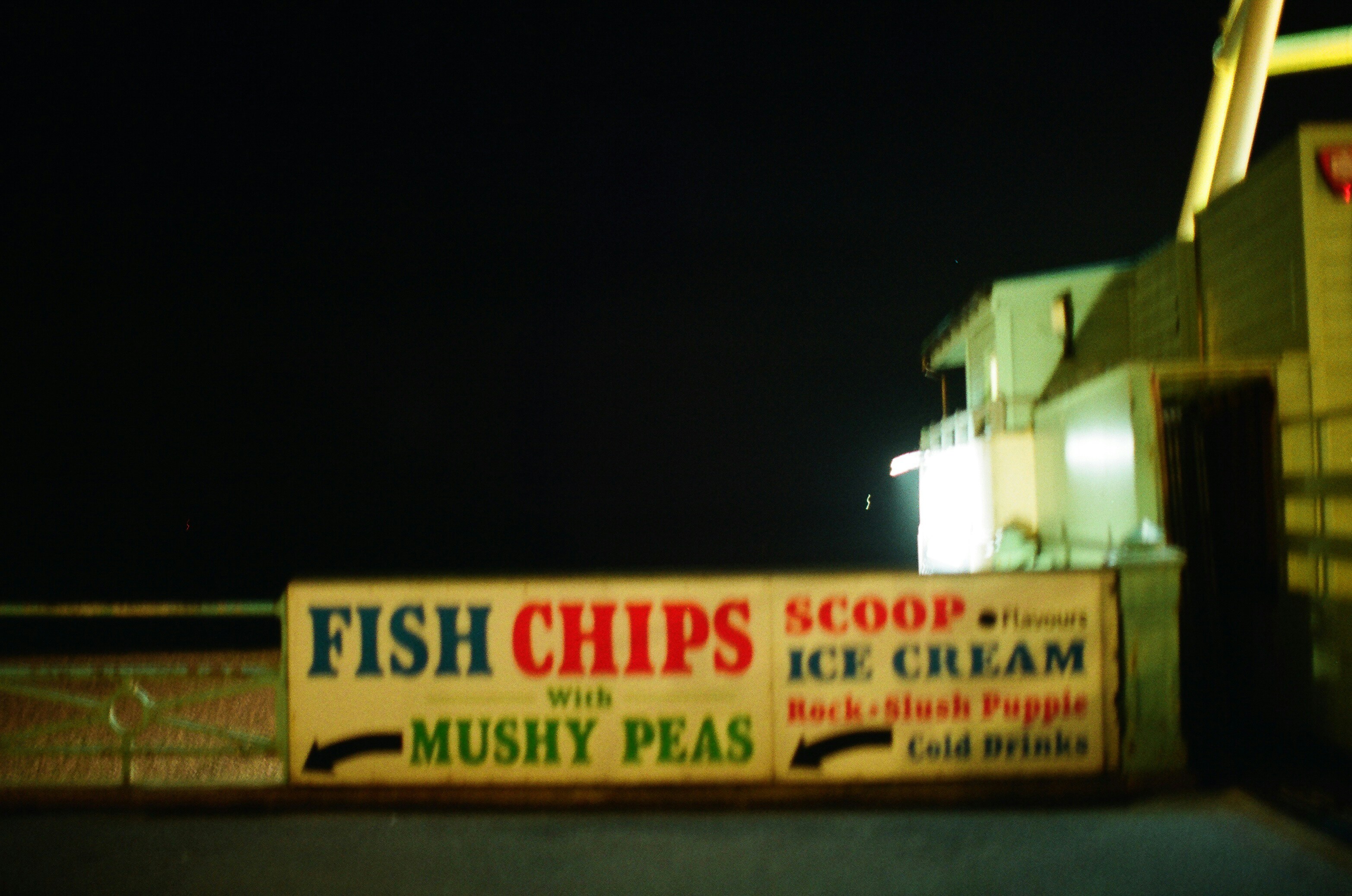 Fish chips, ice cream, and cold drinks sign at night