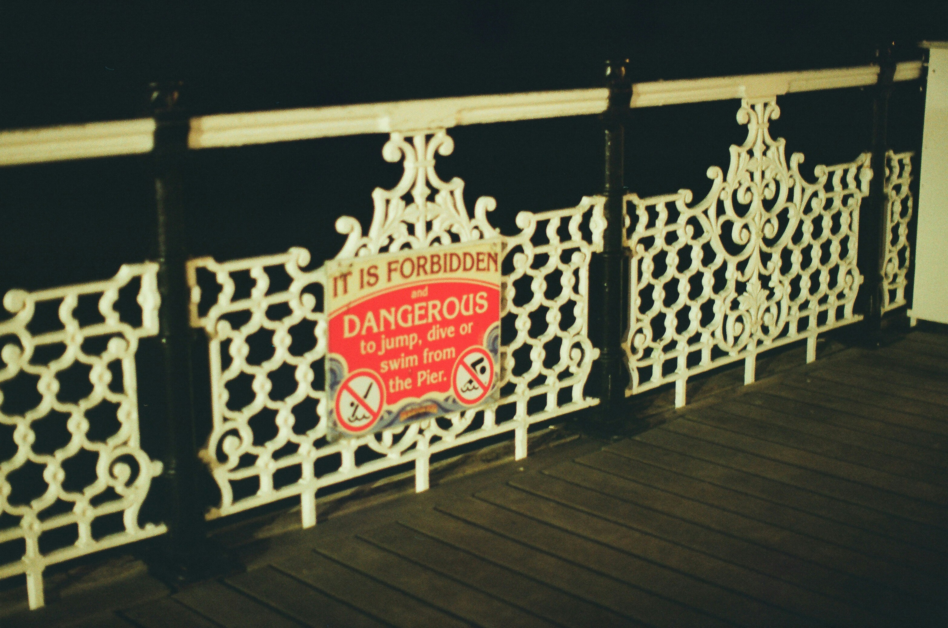 White ornate railing with a red danger sign.