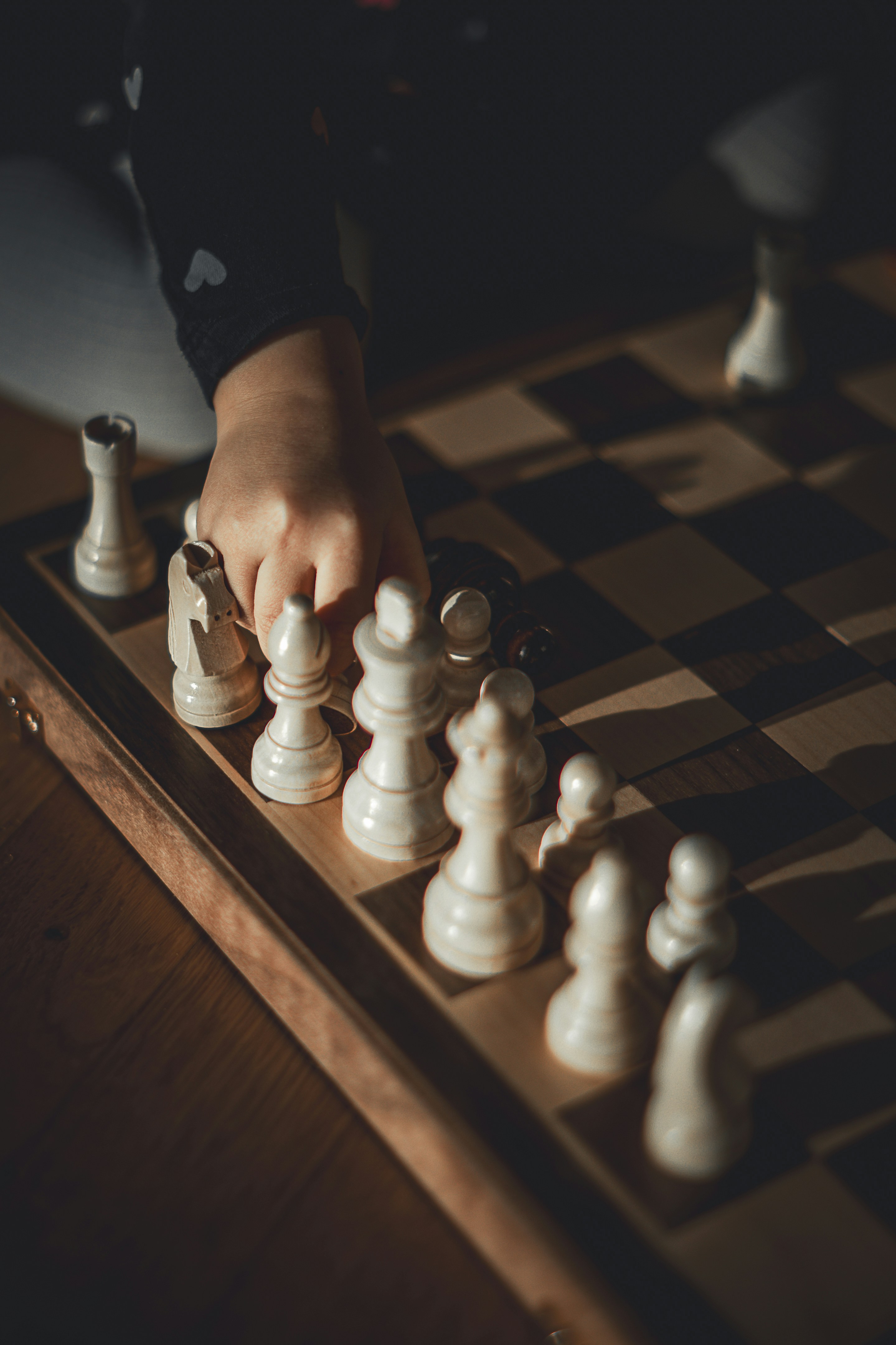 Child's hand moving a chess piece on board