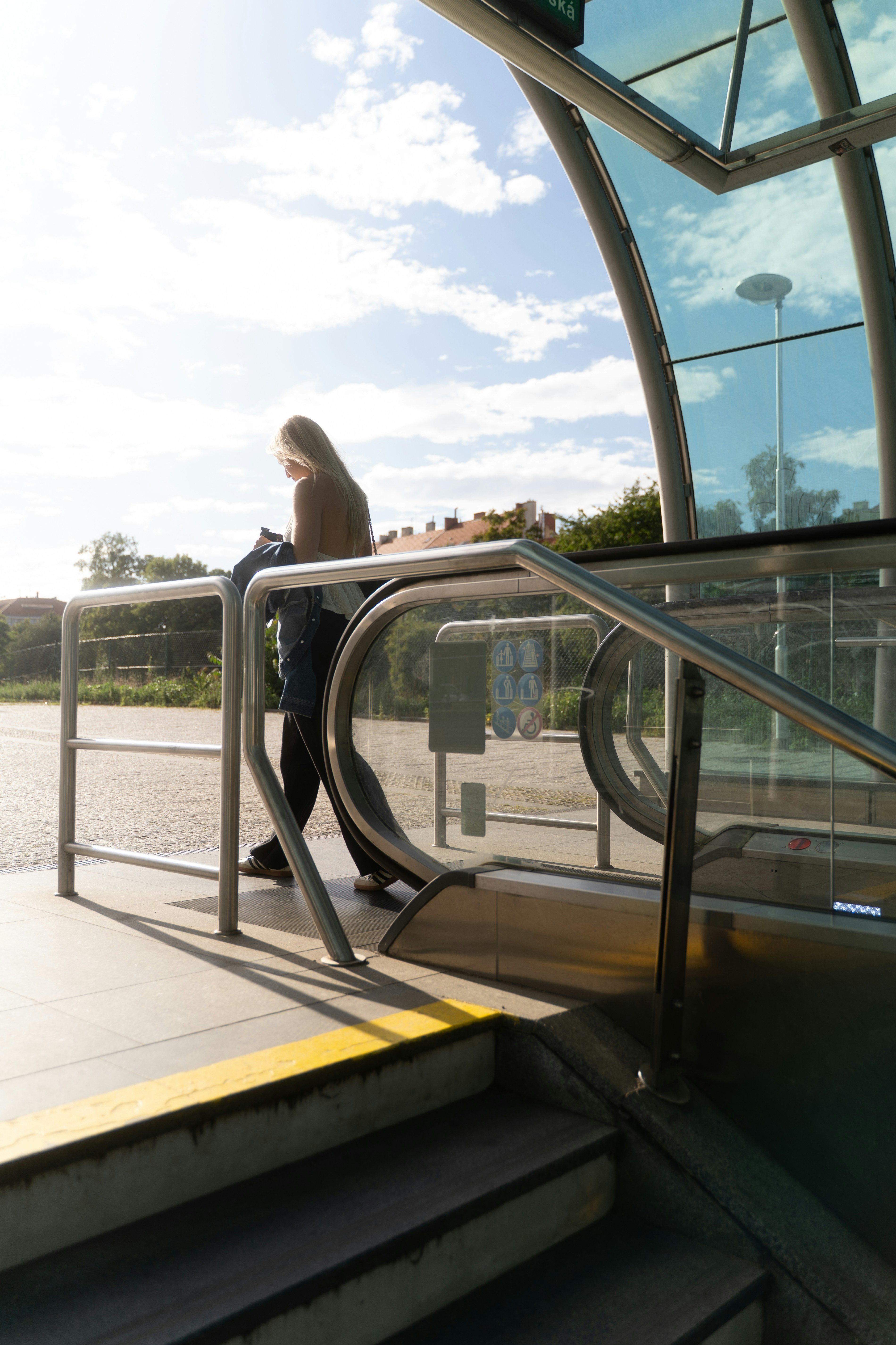 Woman standing by an escalator at a station