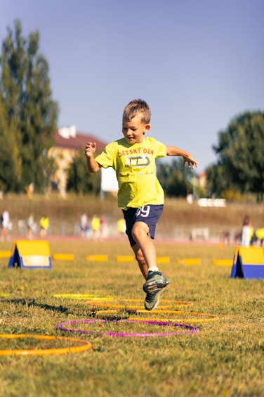 Young boy jumps through hoops during outdoor activity.