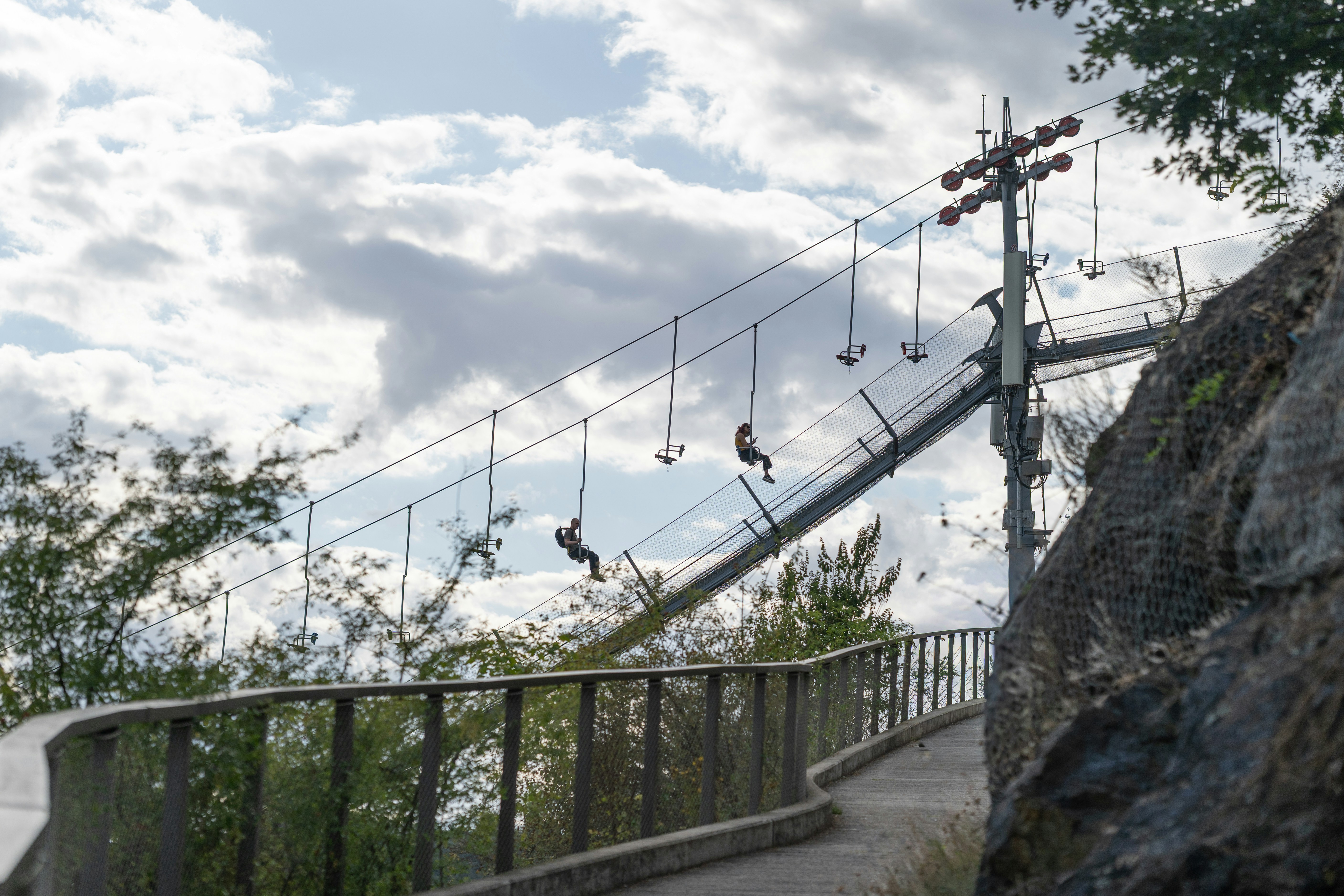 People zip-lining across a suspension bridge