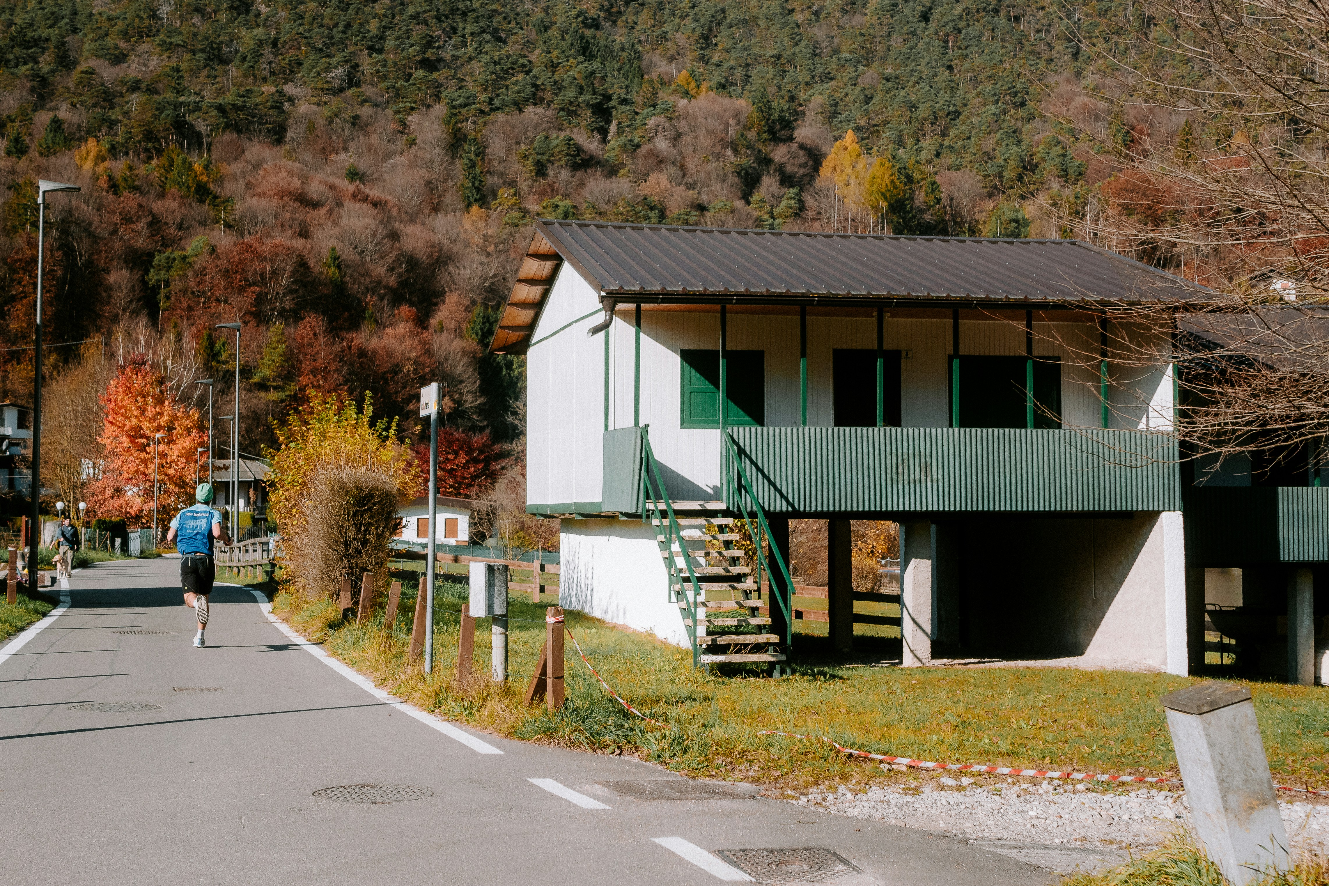 Runner on road by building with green shutters