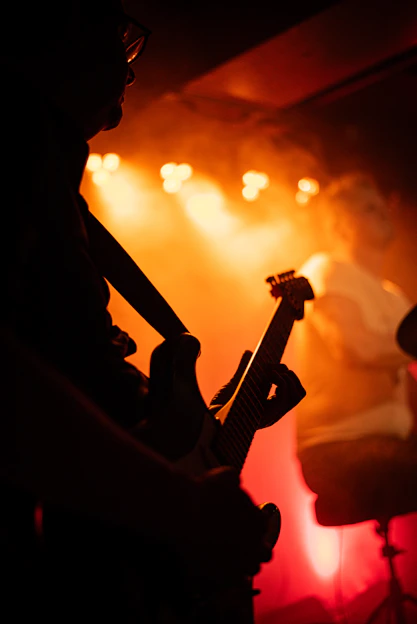 Guitarist performing on stage with orange lights