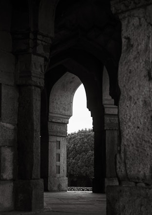 Arched stone passageway leading to trees