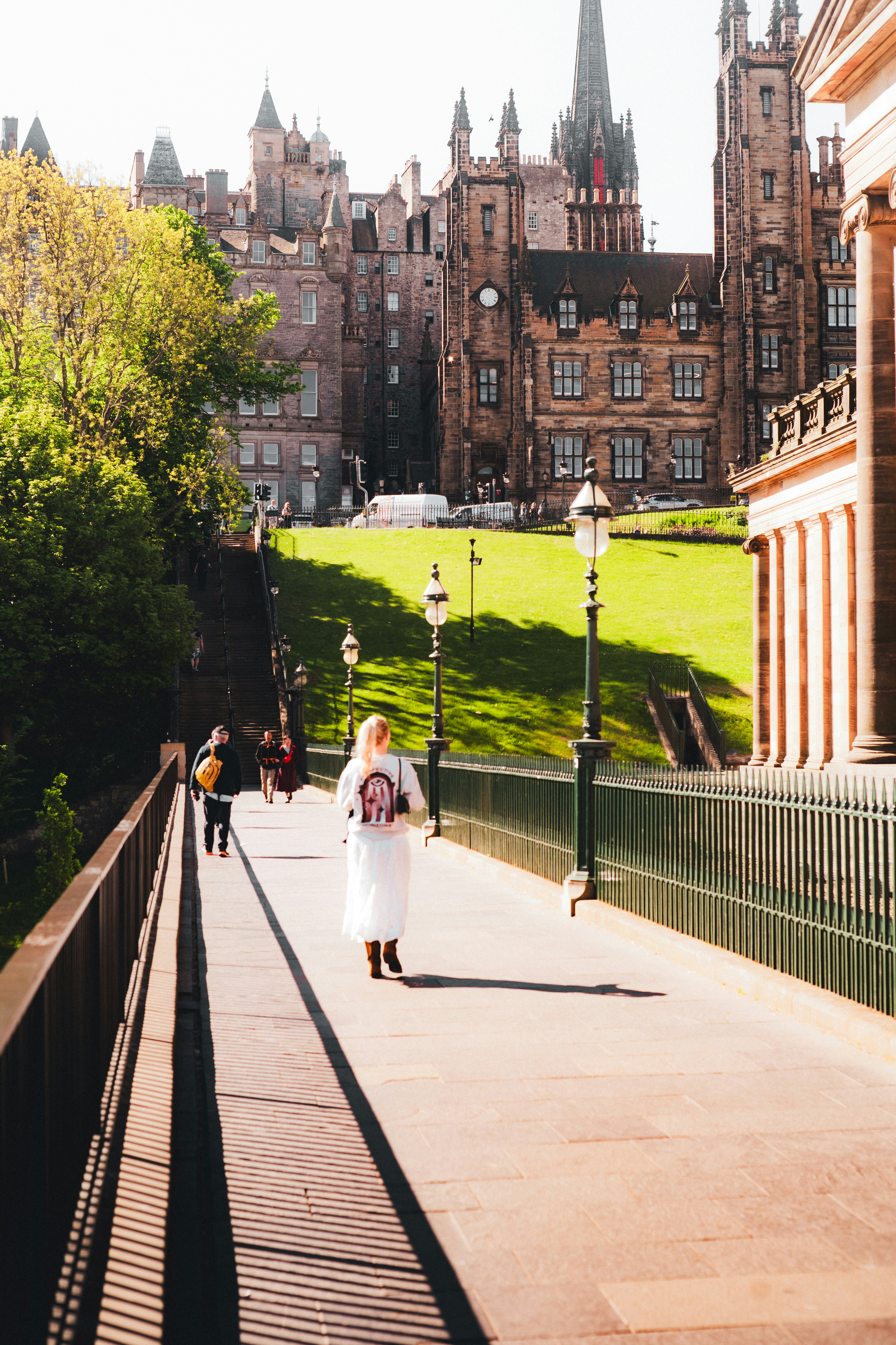 People walking on a bridge with historic buildings behind
