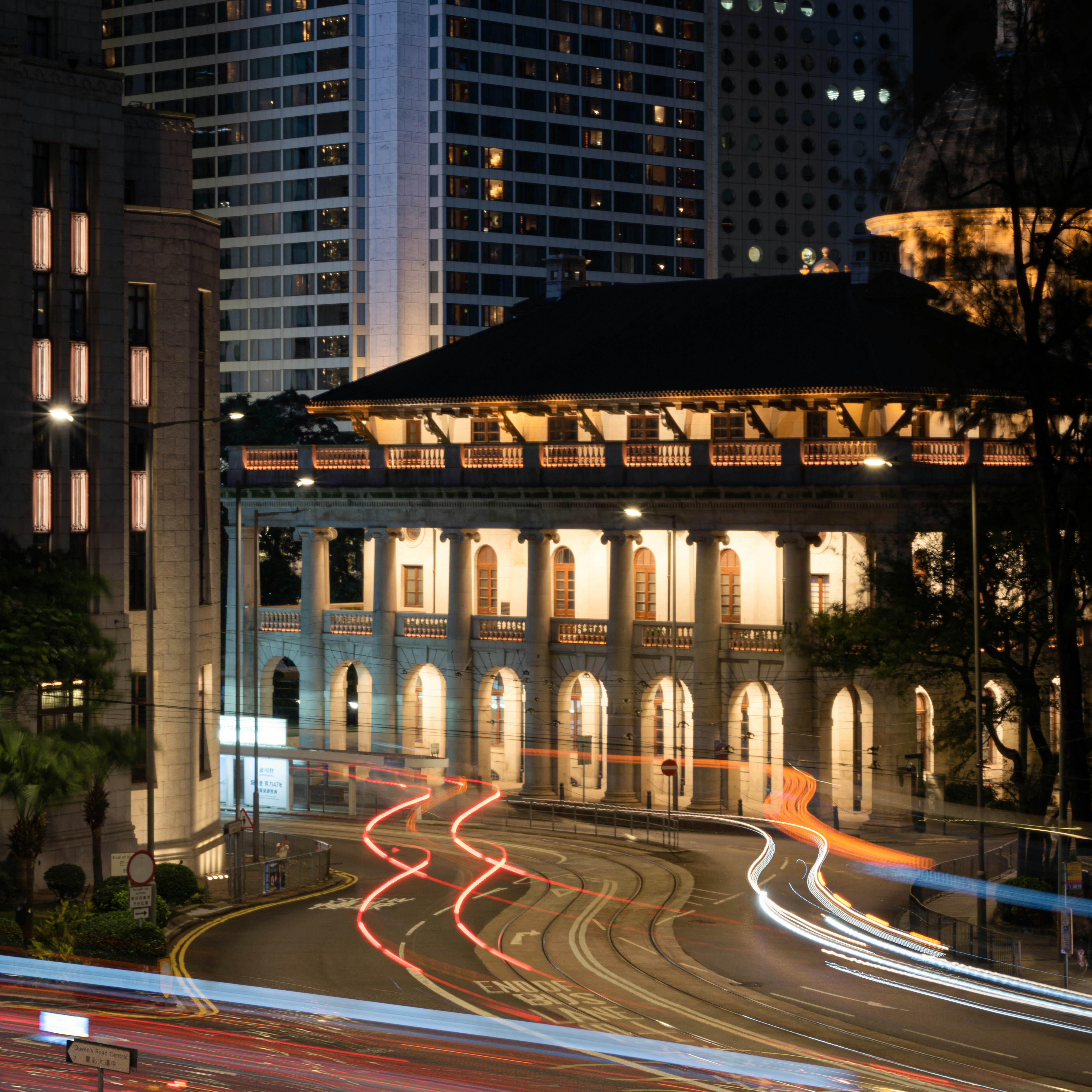 City street at night with light trails from vehicles.