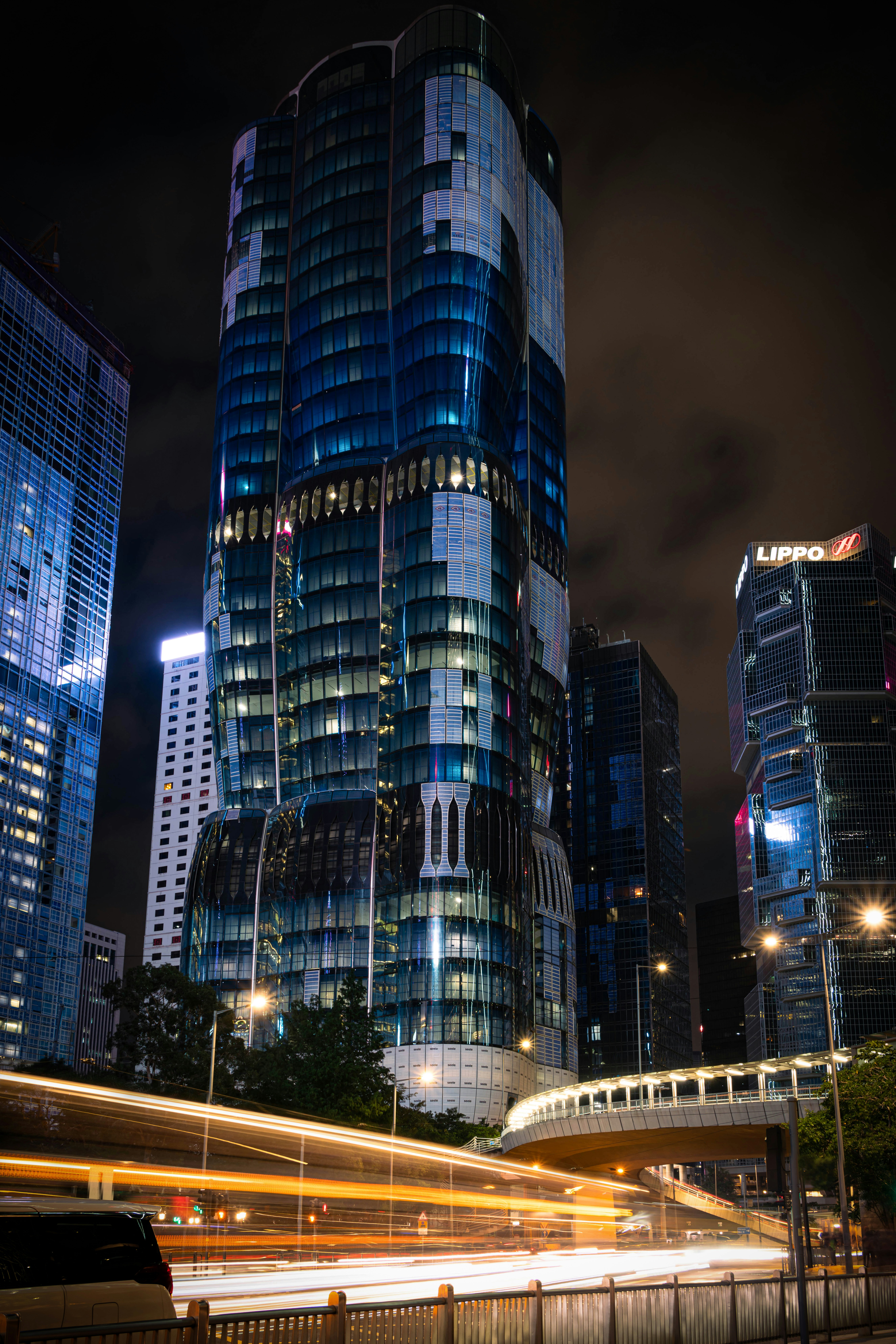 Modern skyscrapers illuminated at night with light trails.