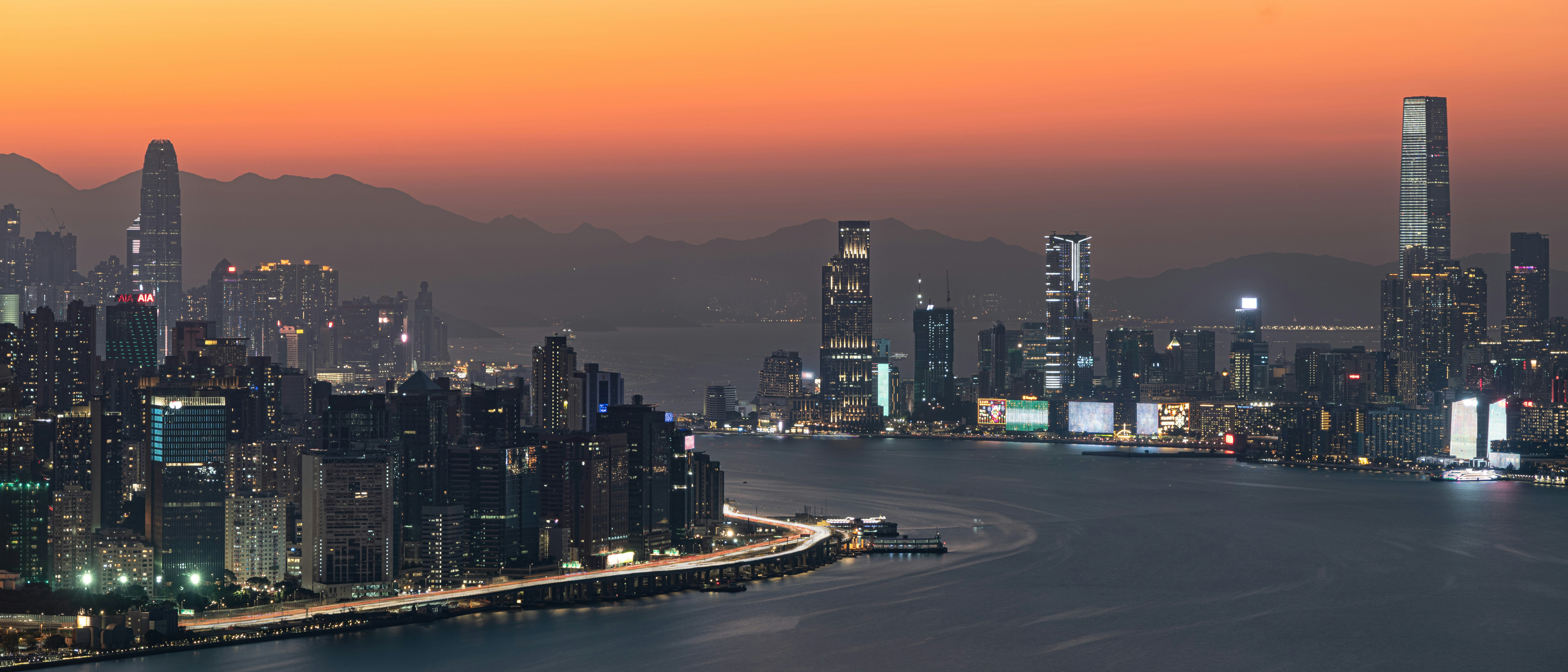 City skyline illuminated at dusk with orange sky.
