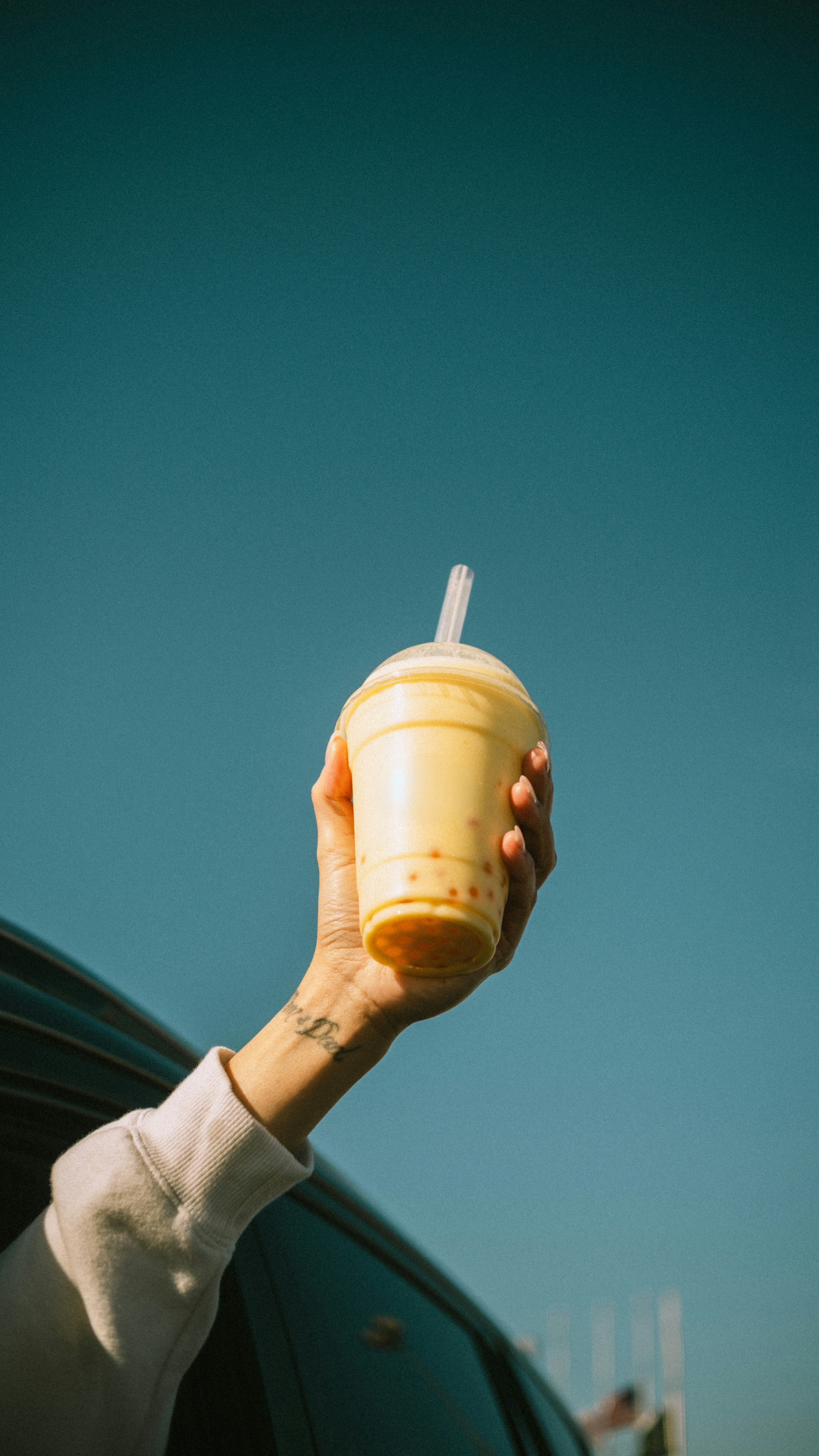 Hand holding a bubble tea out of car window
