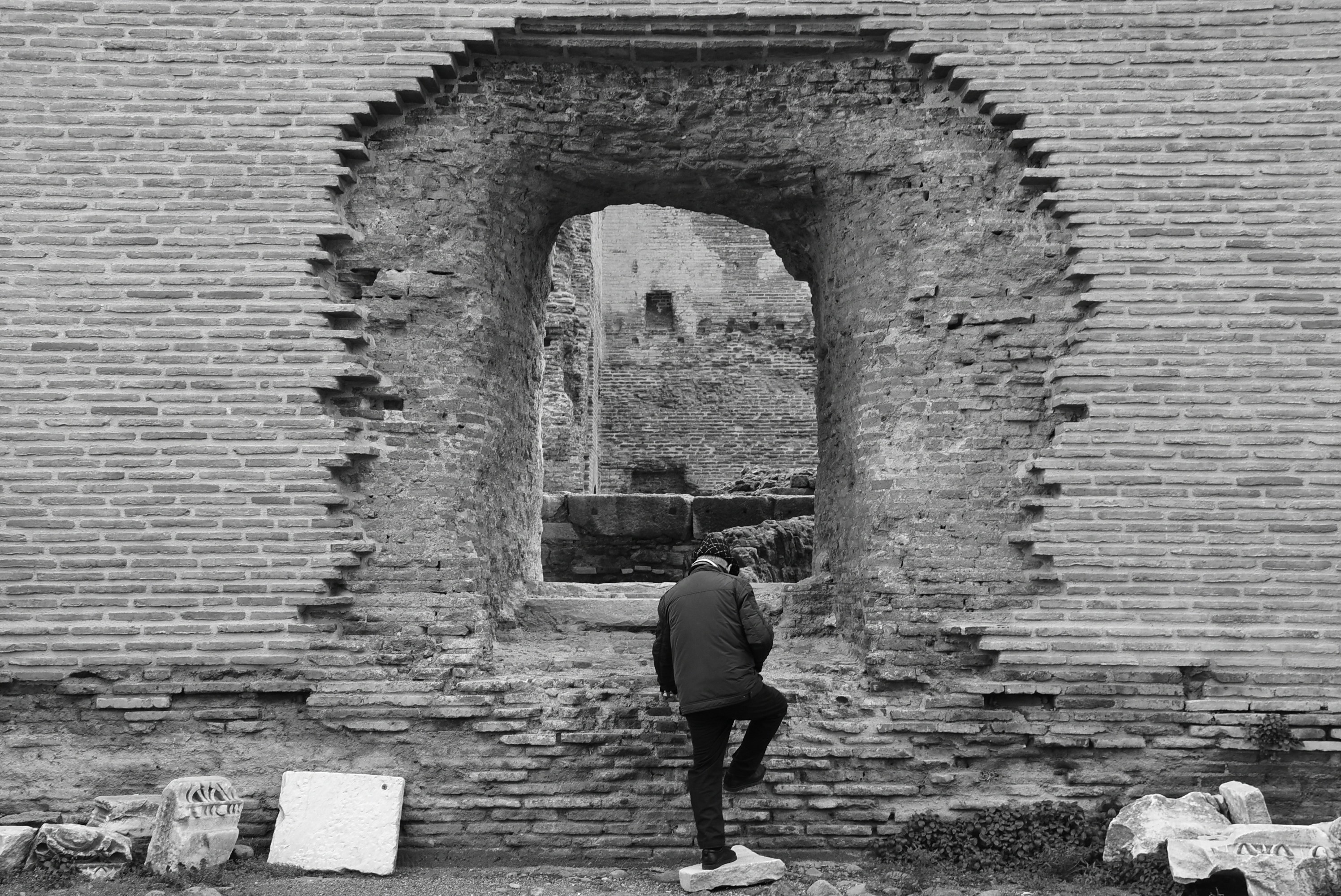 Man climbing through a ruined brick archway