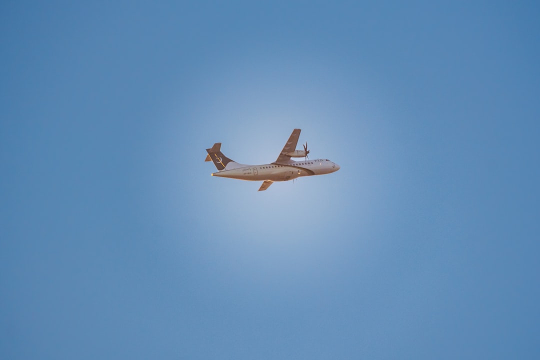 An airplane flies across a clear blue sky.