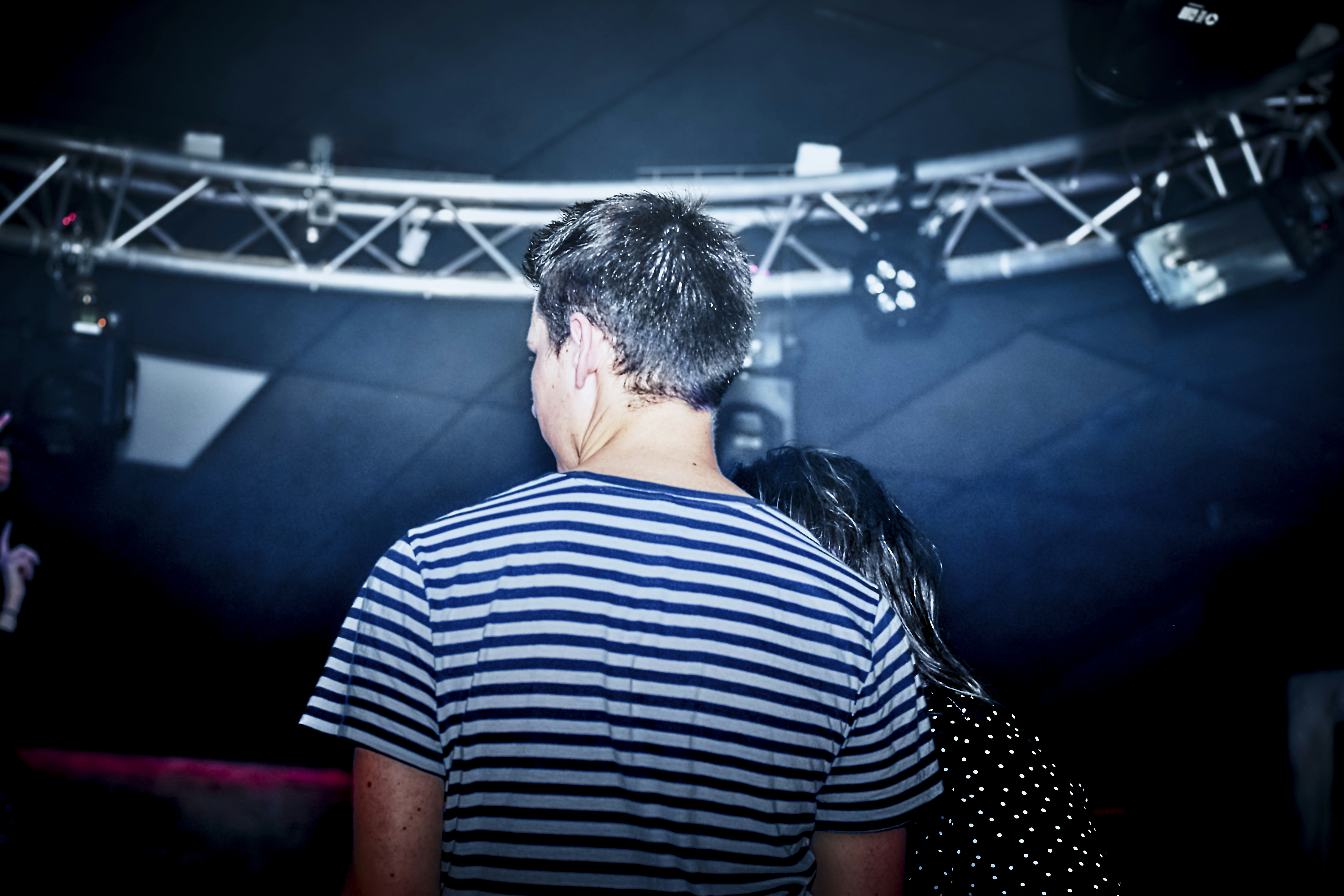 Man in striped shirt at concert venue with club lights